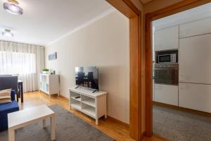 a living room with a couch and a tv and a kitchen at Porto FishLand Apartment in Matosinhos