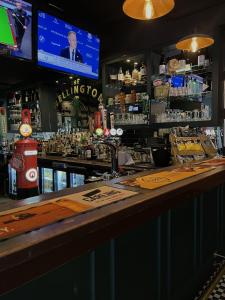 eine Bar mit einem TV und einer Theke in der Unterkunft The Wellington Hotel Birmingham - Breakfast Included City Centre Near O2 Academy in Birmingham