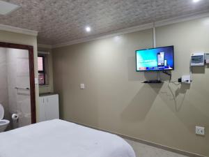 a bedroom with a bed and a tv on the wall at Airport Airbnb in Richards Bay