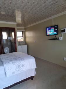 1 dormitorio con 1 cama y TV de pantalla plana en Airport Airbnb, en Richards Bay