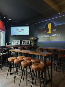 - un bar avec des tables et des tabourets en bois dans un restaurant dans l'établissement The Wellington Hotel Birmingham - Breakfast Included City Centre Near O2 Academy, à Birmingham