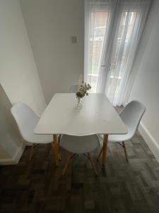 uma mesa branca com cadeiras brancas e um vaso de flores sobre ela em Elegant 3 Bedroom Apartment em Rowley Regis