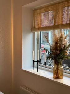a window sill with a vase of flowers and two candles at Skandinavisk City-lejlighed! in Odense