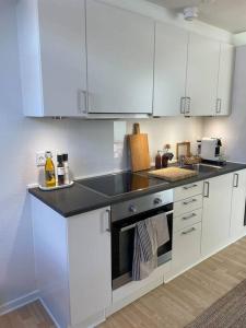 a kitchen with white cabinets and a black counter top at Skandinavisk City-lejlighed! in Odense