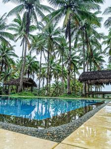 a resort swimming pool with palm trees in the background at Caliraya Ecoville Recreation and Farm Resort in Cavinti