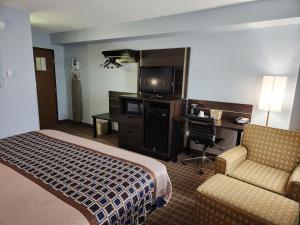Habitación de hotel con cama, escritorio y TV. en Stillwater Inn & Suites, en Stillwater