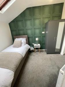 um quarto com uma cama e uma parede verde em Elegant 3 Bedroom Apartment em Rowley Regis