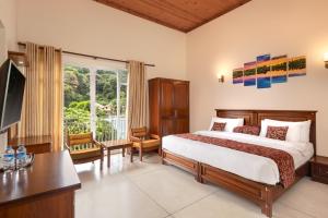 a bedroom with a bed and a desk and a window at Hotel Cassendra in Kandy