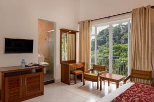 um quarto de hotel com uma cama, uma secretária e uma janela em Hotel Cassendra em Kandy