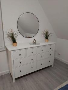 a dresser with a mirror and two plants on it at Wohnung Sonnenschein Wolgast in Wolgast