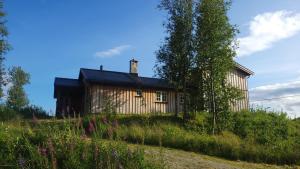 uma casa ao lado de uma colina com flores em Solrik og flott hytte i Havsdalen em Geilo