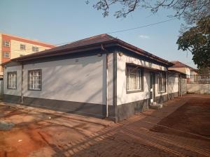 un pequeño edificio blanco con techo marrón en Las Palmas Day & Night Guest House, en Pretoria