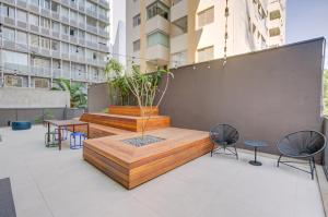 a patio with a bench and tables and chairs at Roomo OY Frei Caneca Residencial in São Paulo