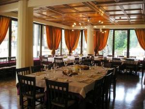 ein großes Esszimmer mit Tischen, Stühlen und Fenstern in der Unterkunft Locanda Seggiovia in Recoaro Terme