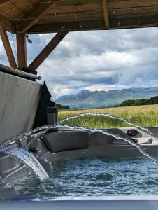 un barco en el agua con una manguera de agua en FINN VILLAGE "Mountain View Cottage" Private Garden, 9-seater Hot Tub, Firepit & Pizza Stove, en Drymen