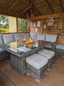 un patio con mesa, sillas y fogata en FINN VILLAGE "Mountain View Cottage" Private Garden, 9-seater Hot Tub, Firepit & Pizza Stove, en Drymen