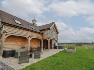 uma casa de madeira com um pátio e um quintal em Hallgarth Farm Holiday Lodge em Pershore