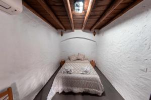 a small bedroom with a bed in a white wall at Casa Rural El Palomeque 