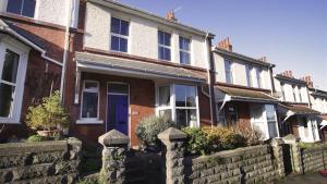 a brick house with a blue door and a stone fence at Oakland Road, Mumbles in The Mumbles