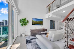una sala de estar con muebles blancos y ventanas grandes. en Stunning 1 Bedroom Loft in The Heart of Brickell, en Miami
