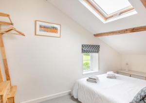 a white bedroom with a bed and a window at Appletree Cottage in Thornage