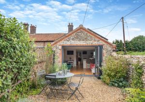 a small brick house with a table and chairs outside at Appletree Cottage in Thornage