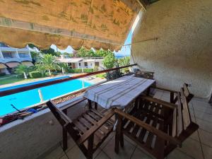 a wooden table and chairs on a balcony with a pool at MIRAMARE in Nea Makri