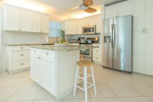 a kitchen with white cabinets and a stainless steel refrigerator at Hutchinson Island Beachfront - 2bd, 2ba Ensuite in Fort Pierce