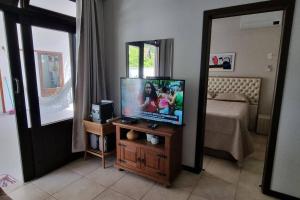 a living room with a flat screen tv and a mirror at Apto na Bela Lagoa da Conceição in Florianópolis