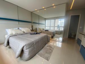 a bedroom with two beds and a large window at Flat Studio DNA Smart style in Goiânia