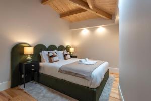 a bedroom with a large bed with a green headboard at Ando Living - Flores Townhouse in Porto