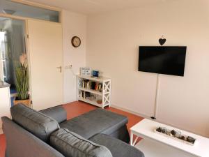 Il comprend un salon doté d'un canapé et d'une télévision à écran plat. dans l'établissement Dünenglück, à Buren