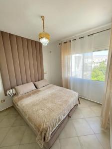 een slaapkamer met een groot bed en een groot raam bij Appartement avec piscine taghazout imi Ouaddar in Agadir nʼ Aït Sa