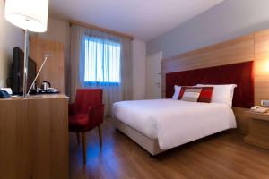 a bedroom with a bed and a desk with a television at Dolce by Wyndham Milan Malpensa in Somma Lombardo