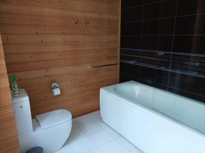 a bathroom with a white toilet and a bath tub at Jaunakmeņi in Priežmale