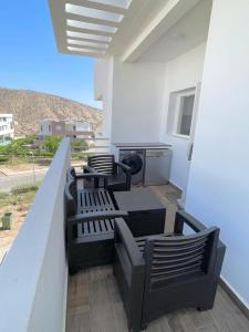 un patio con 4 sillas, una mesa y una parrilla en Appartement avec piscine taghazout imi Ouaddar en Agadir nʼ Aït Sa