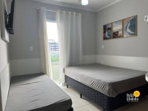 ein Schlafzimmer mit zwei Betten und einem Fenster in der Unterkunft Conforto, 2 vagas garag lazer a poucos passos do mar! Apto 306/B, Ana Luiza - Praia Grande in Ubatuba + 61 Fotos