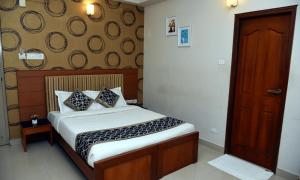1 dormitorio con 1 cama y puerta de madera en Vel Residency, en Thanjāvūr