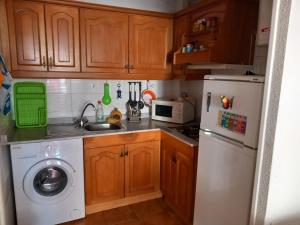 a kitchen with a white refrigerator and a washing machine at Apartamento Santa Pola, en Playa del Tamarit con piscina. in Santa Pola