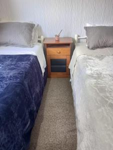 two beds in a room with a nightstand between them at Hospedaje depto 2 habitaciones in Coronel