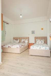 Habitación con 2 camas, paredes blancas y suelo de madera. en Rooms by the sea, en Himare