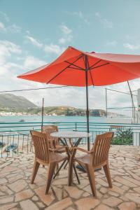 希馬拉的住宿－Rooms by the sea，一张桌子和两把椅子,配有红色雨伞