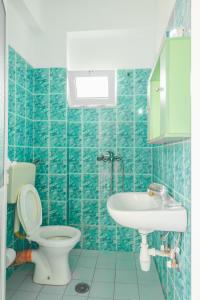 Baño de azulejos azules con aseo y lavamanos en Rooms by the sea, en Himare