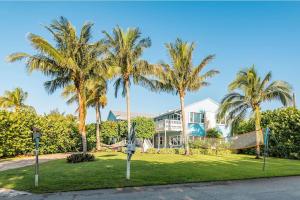 a house with palm trees in front of it at Secluded Beachfront Vibes - Surf & Pet Friendly in Fort Pierce