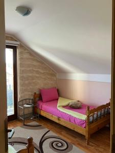 um quarto com uma cama de madeira e lençóis cor-de-rosa em Apartmani Rada em Zlatibor