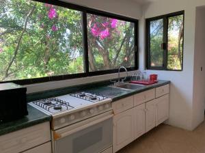 a kitchen with a stove and a sink and windows at Brisas el Valle in Temixco