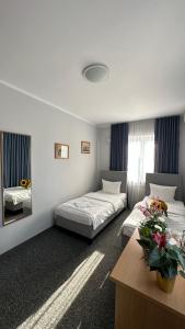 Pokój z 2 łóżkami i stołem z kwiatami w obiekcie Lezzet Hotel & Turkish Restaurant w Warszawie