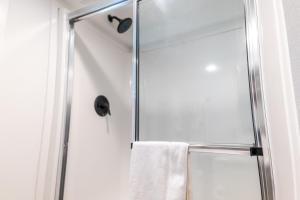 a shower with a glass door and a towel at HTR TX Hill Country Campground in Kerrville