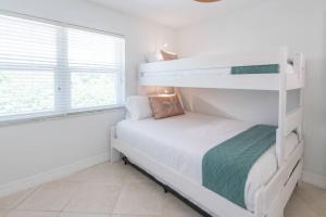 a bedroom with two bunk beds and a window at Steps to Private Beach - Sand, Surf, Sun - 2bd,2ba in Fort Pierce