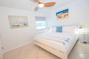a white bedroom with a bed and a ceiling fan at Upper-Floor Ocean Breeze - Surf Views 2BR in Fort Pierce